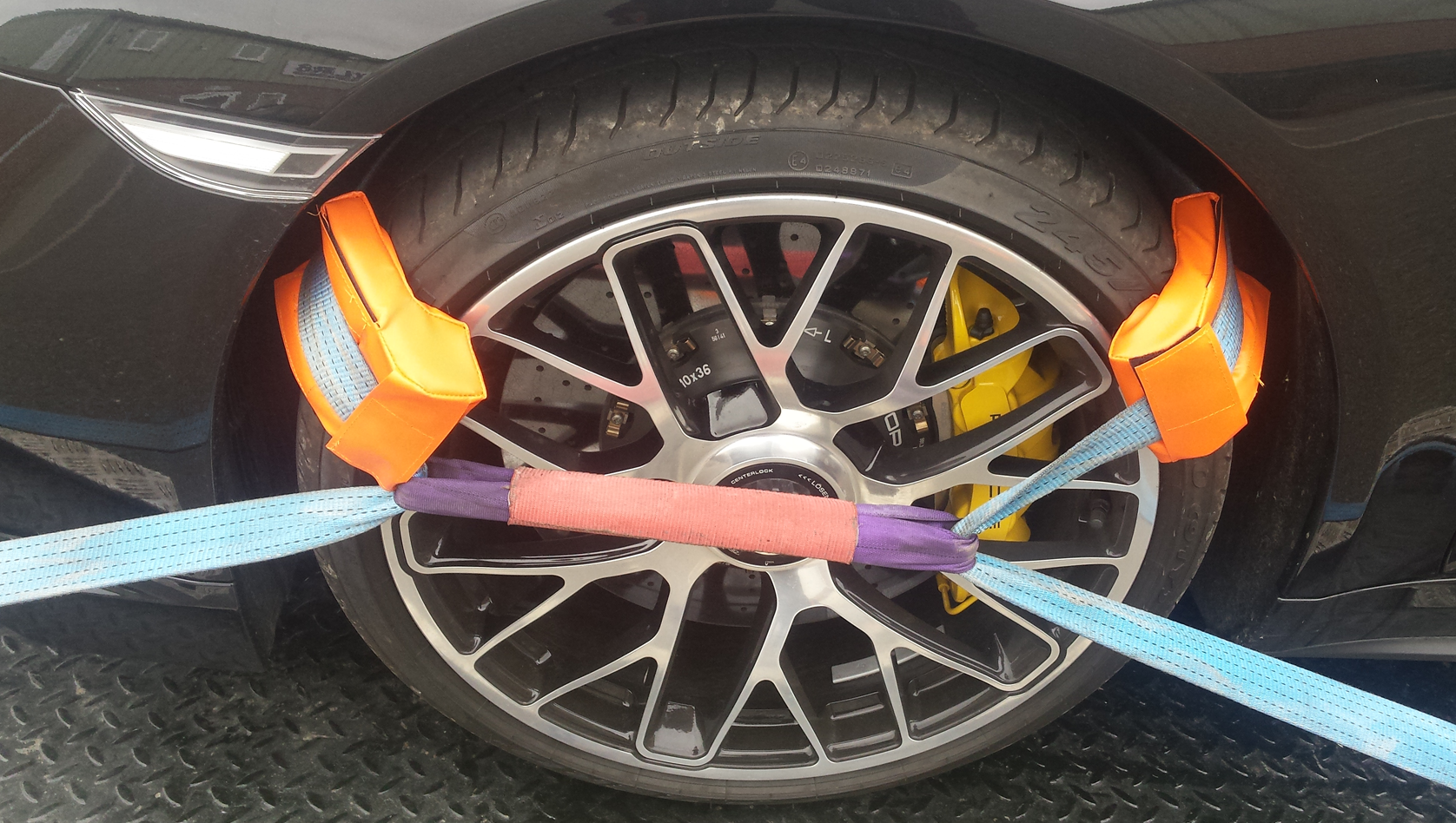 Image shows a car wheel being secured by straps