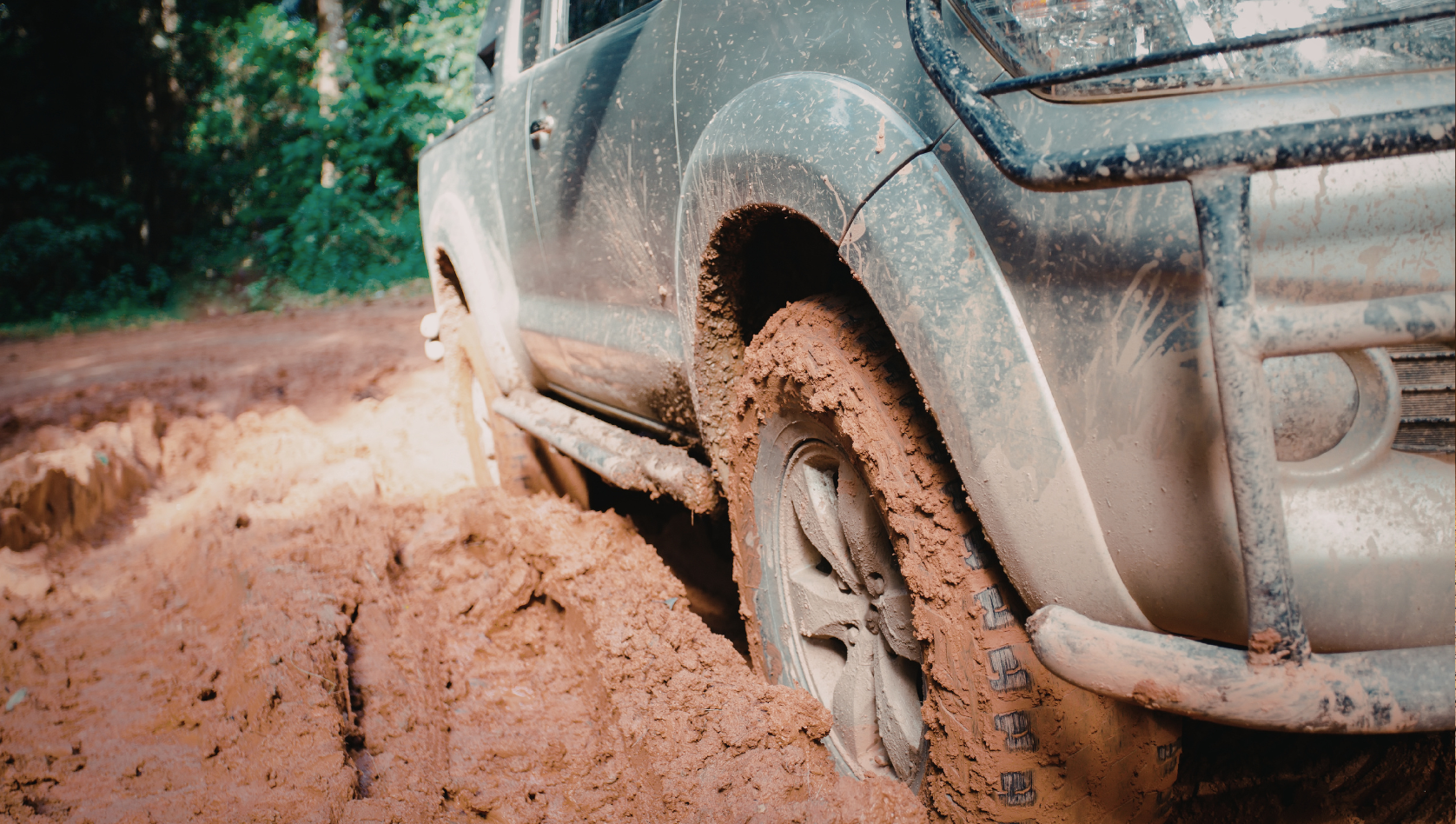 Image shows the tyres of a car stuck in mud. Image depicts February recovery challenges