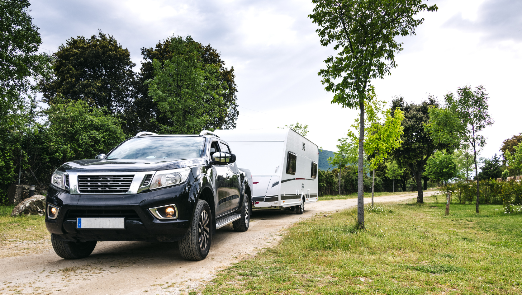 Image shows a large car towing a caravan down a country road